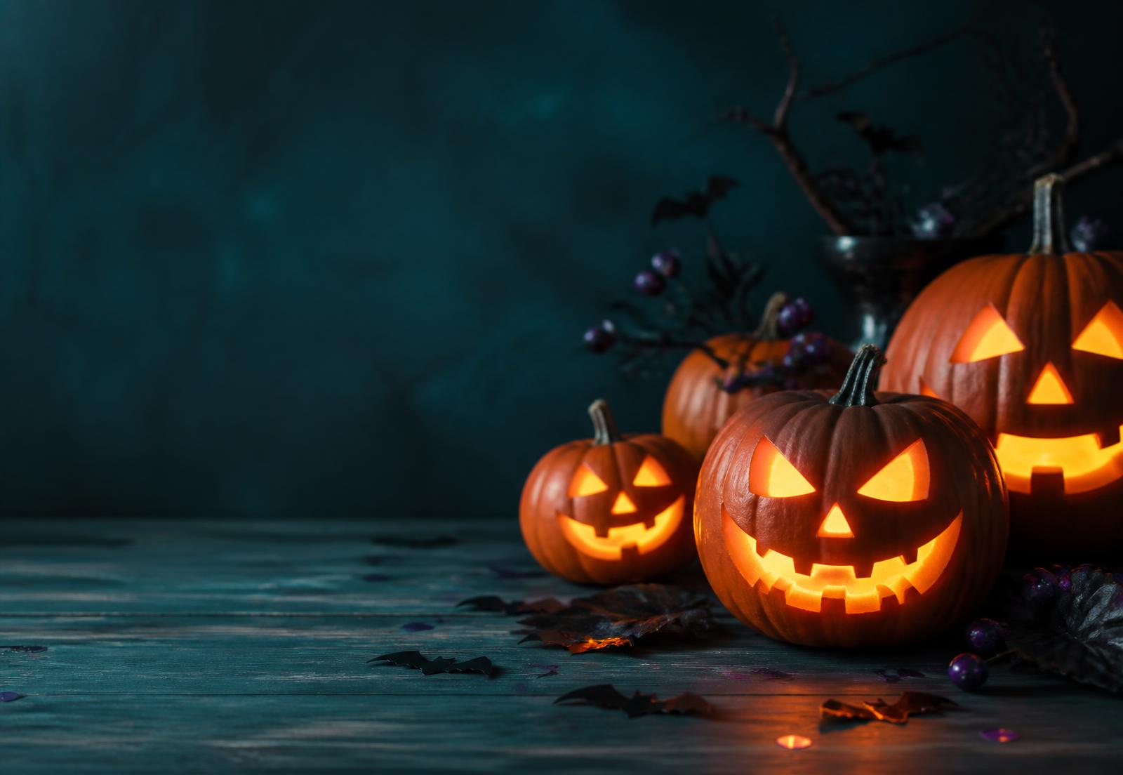 Glowing carved jack-o'-lanterns on a teal wood table